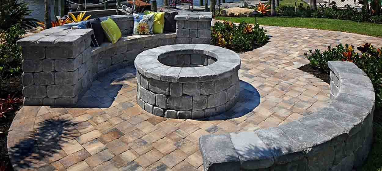 Charcoal paver waterfront patio with circular fire pit and seat walls